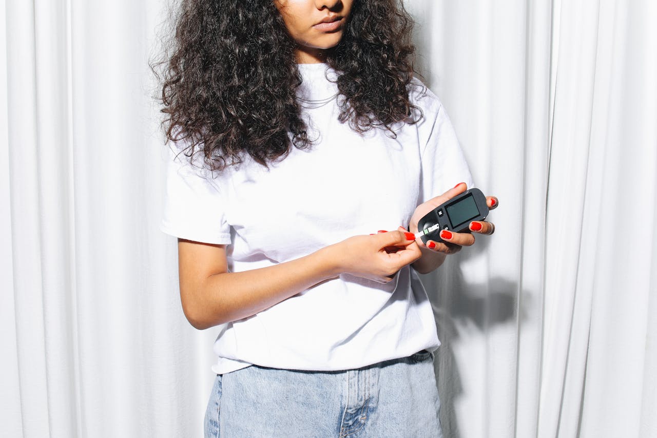 A woman using a glucometer to check blood sugar levels indoors, highlighting diabetes care.